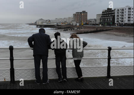 Menschen stehen auf Worthing Pier und beobachten die großen Wellen auf den Strand am Neujahrstag in Worthing, West Sussex, England. Stockfoto