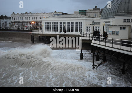 Menschen auf Worthing Pier stehen und beobachten Sie die großen Wellen auf den Strand am Neujahrstag in Worthing, West Sussex, England. Stockfoto