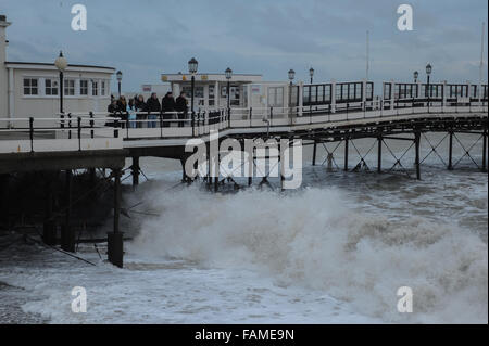 Menschen stehen auf Worthing Pier und beobachten die großen Wellen auf den Strand am Neujahrstag in Worthing, West Sussex, England. Stockfoto