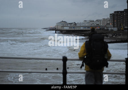 Ein Mann steht auf Worthing Pier beobachten die großen Wellen auf den Strand am Neujahrstag in Worthing, West Sussex, England. Stockfoto
