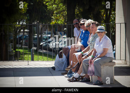 Menschen saßen auf einer Bank einen Bus warten. Albufeira, Algarve, Portugal Stockfoto