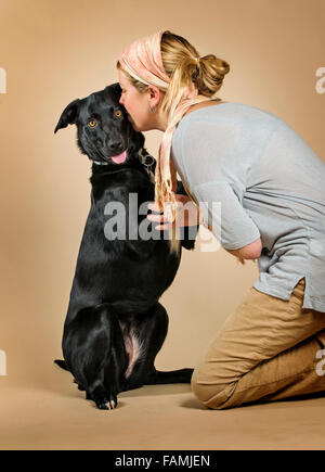 Studioportrait attraktive blonde Kaukasische Frau mit ihrem schwarzen Laborador - Collie Mix Rasse Hund Stockfoto