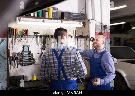 glückliche Europäische Männer in Overalls arbeiten bei carshop Stockfoto