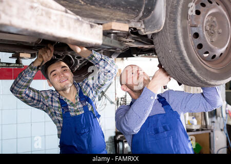 Porträt, Lächeln zwei Männer in Overalls bei Autowerkstatt arbeiten Stockfoto