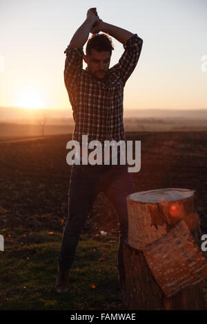 Die stilvolle Holzfäller Holzhacken bei Sonnenuntergang. Stockfoto