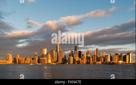 Die Skyline der Innenstadt von Manhattan golden erscheint, wie der Sonnenuntergang Gegenteil in das Glas der Wolkenkratzer spiegelt Stockfoto