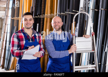 Arbeiter in Overall Betrieb in Drehbank, seinen Chef mit Papieren in der Nähe Stockfoto