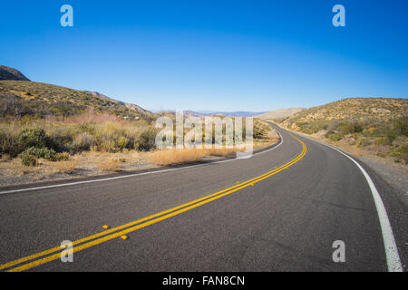 Lange Biegekurve in der Straße in der trockenen Wüste Wildnis des amerikanischen Südwestens. Stockfoto