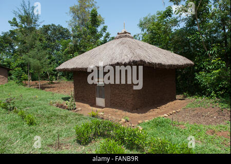 Hausgemachtes aus Schlamm mit einem Strohdach, mit einem gepflegten Garten im ländlichen Kenia. Stockfoto