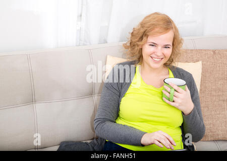 Eine junge plus Größe Frau mit einem Tablet-PC auf einem Sofa sitzt. Stockfoto