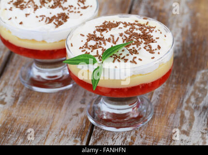 Traditionellen Erdbeer Trifle Dessert mit frischer Sahne und bestreut mit Schokolade auf rustikalen Holz Stockfoto