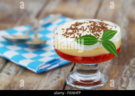 Traditionellen Erdbeer Trifle Dessert mit frischer Sahne und bestreut mit Schokolade auf rustikalen Holz Stockfoto