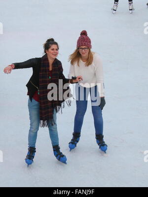Zwei niederländische Mädchen Skaten auf der temporäre Eisbahn am Museumplein (Museumsplatz), Amsterdam, Niederlande Stockfoto