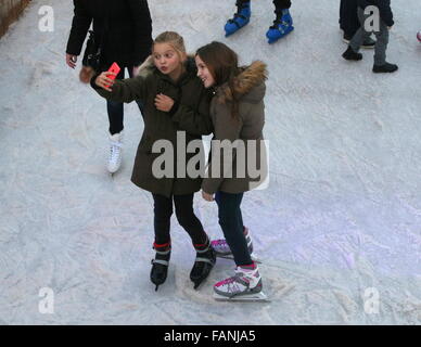 Zwei Mädchen, die ein Selbstporträt. Menschen, die Skaten auf der temporäre Eisbahn am Museumplein (Museumsplatz), Amsterdam, Niederlande Stockfoto