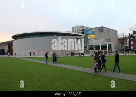 Einheimische und Touristen am Museumplein (Museumsplatz), Amsterdam, Niederlande. Van Gogh Museum im Hintergrund renoviert. Stockfoto