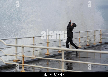 Aberystwyth, Wales, UK. 2. Januar 2016. UK-Wetter: Trotz einer Flaute in den jüngsten stürmischen Wetter erzeugt ein erheblicher Wellengang dramatische Wellen gegen die Promenade. Hier ist ein kleiner Junge gesehen die Wellen ausweichen. Bildnachweis: Alan Hale/Alamy Live-Nachrichten Stockfoto