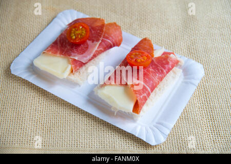 Spanische Tapa: Käse mit iberischem Schinken mit Kirschtomaten auf geschnittenem Brot eingewickelt. Stockfoto