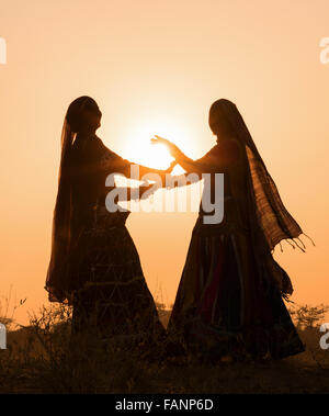 Silhouette von zwei Gypsy tanzende Frauen einen traditionellen Tanz bei Sonnenuntergang, Pushkar Camel Fair, Pushkar, Rajasthan, Indien Stockfoto