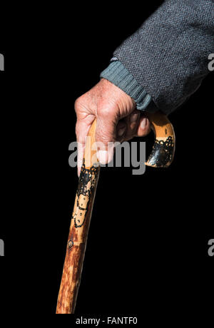 Ältere Mann, hält einen traditionellen hölzernen Gehstock auf schwarzem Hintergrund isoliert. Stick dient zur Unterstützung und Hilfe Stockfoto