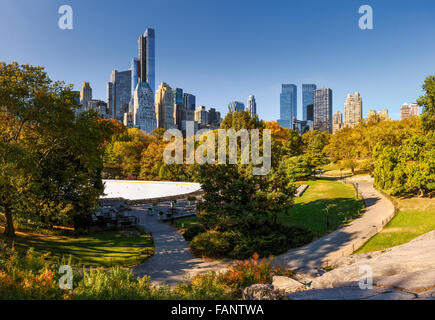 Fallen im Central Park: Wollman Rink und Manhattan Wolkenkratzer. Stadtbild Herbst Blick auf Central Park South, New York City Stockfoto