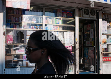 Schwarze Frau vor einem Lebensmittelgeschäft in Harlem, New York, USA. Coolcat Beauty Supply Dr Martin Luther King Jr. Boulevard Harlem New York Manhattan-USA Stockfoto