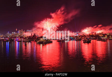 Sydney City Feuerwerk über dem CBD Wahrzeichen mit Wolkenkratzern und die Harbour Bridge hinter angedockten Boote und Yachten auf stilles Wasser Stockfoto