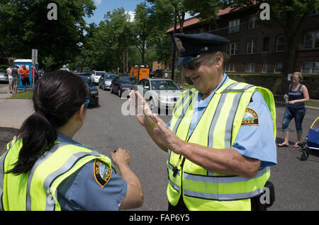 Senior Reserve Polizist demonstrieren Hand signalisiert asiatischen Polizistin. Große alte Straße Messetage. St Paul Minnesota MN USA Stockfoto