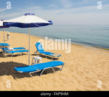 Sonnenschirme von weißen und blauen Farben und blauen Chaise Lounges am Sandstrand und Meer, aufgenommen am Sants Constantine und Hele Stockfoto