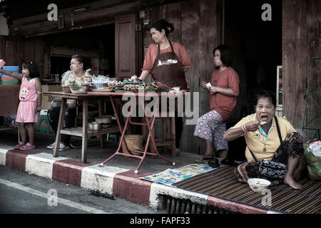 Thailand Familie mit Lebensmitteln verkauft und verzehrt von der Bürgersteig vor ihrem Haus. Thailand S. E. Asien Stockfoto