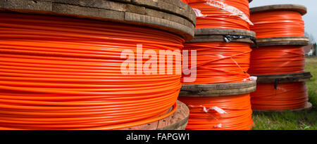 Kabeltrommeln mit orange Glasfaserkabel auf einer Baustelle Stockfoto