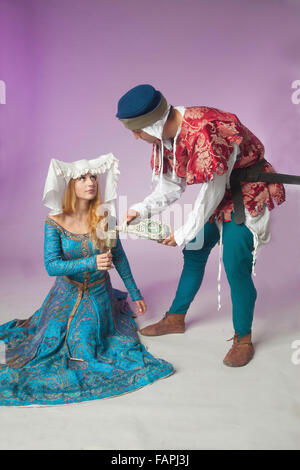 Studioaufnahme jungen Paares in mittelalterlichen Kostümen gekleidet, als eine schöne edle Dame und ein wirbt Man Gießen Weinstock Stockfoto