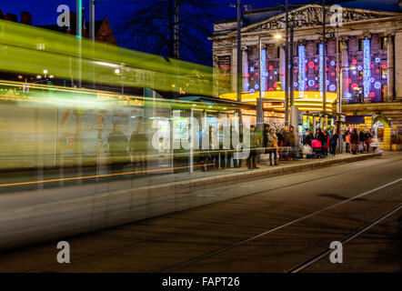 Ein Nottingham NCT Straßenbahn ankommt - in Bewegung verschwommen, als Passagiere warten. In Nottingham Marktplatz zu Weihnachten. Stockfoto