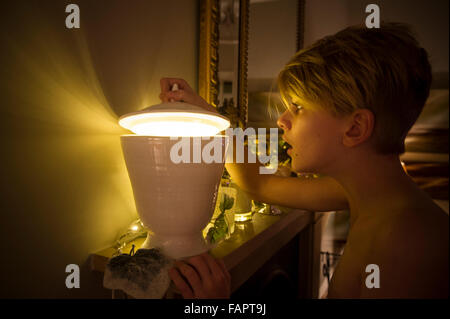 Ein kleiner Junge schaut in eine geheimnisvolle Schüssel mit einem magischen hellen Licht Stockfoto