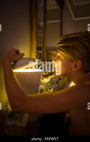 Ein kleiner Junge schaut in eine geheimnisvolle Schüssel mit einem magischen hellen Licht Stockfoto