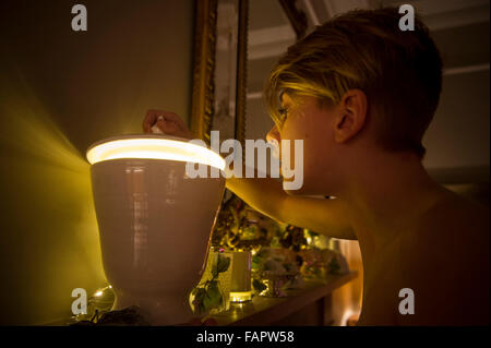 Ein kleiner Junge schaut in eine geheimnisvolle Schüssel mit einem magischen hellen Licht Stockfoto