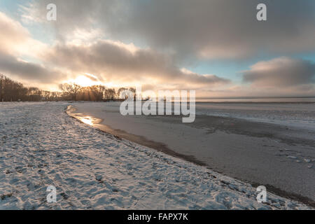 Winterabend am Ufer des Sees mit dem ersten Eis und Schnee. Stockfoto