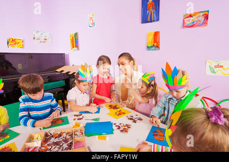 Lehrer hilft Kindern Handwerk Bilder kleben Stockfoto