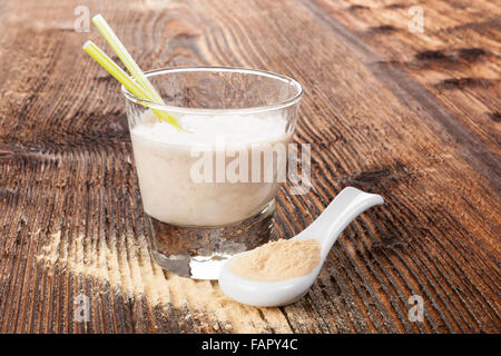 Maca Pulver auf Löffel und Maca Pulver schütteln auf braun alter Holztisch. Gesundes Wohnen, alternative Medizin, rustikalen Stil. Stockfoto