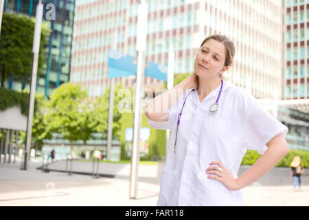 junger Arzt mit Hals Schmerzen nach einem langen anstrengenden Tag im Krankenhaus Stockfoto