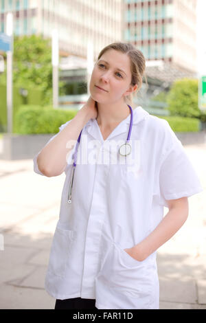 junger Arzt mit Hals Schmerzen nach einem langen Tag bei der Arbeit Stockfoto