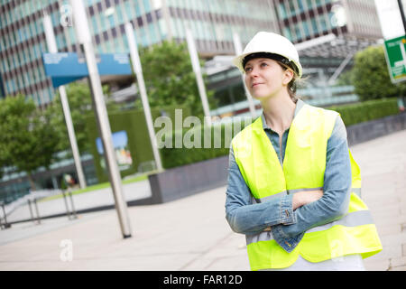 junge Frau trägt ein Counstruction Schutzhelm und gelbe Jacke Stockfoto