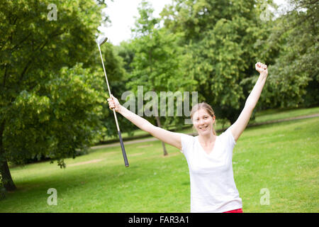 junge Frau feiert ein Hole in one auf dem Golfplatz Stockfoto