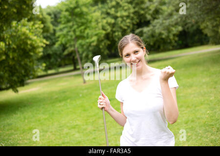 junge Frau feiert ein Hole in one auf dem Golfplatz Stockfoto