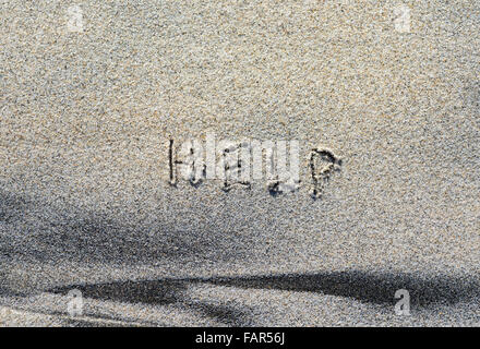 Das Wort Hilfe in Sand geschrieben. Stockfoto