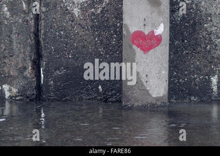 Rotes Herzsymbol auf eine nasse Grunge Wand gemalt Stockfoto