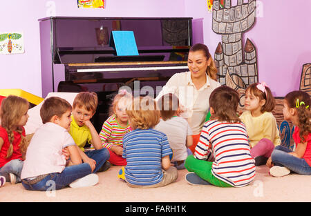 Gruppe von Kindern sitzen und hören Sie Lehrer erzählen Geschichte Stockfoto