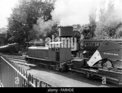 Bahnhof Haworth, West Yorkshire circa 1982 schwarz-weiß Archiv Bild. Heimat der Keighley und Wert Valley Railway, ist die KWVR mit freiwilligen besetzt. Vereinigte Staaten von Amerika Transportation Corps. Klasse S160 2-8-O Nr. 582O, erbaut im Jahre 1945 von Lima in den USA für Service in Europa während des 2. Weltkrieges, 5820 in Großbritannien im Jahr 1977, dämpfen, vorbei an einem Rangierer und Abbau Kran auf dem Hof angekommen. Stockfoto