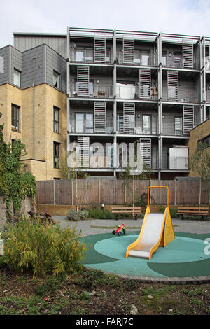 Ein kleiner Garten und Kinder Spielplatz hinter einem neuen Wohnblock in Hackney, East London Stockfoto