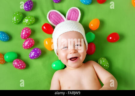 Baby Boy in Hase Hut auf grüne Decke liegend mit Ostereiern Stockfoto