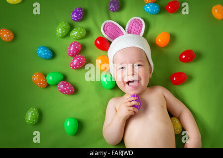 Baby Boy in Hase Hut auf grüne Decke liegend mit Ostereiern Stockfoto